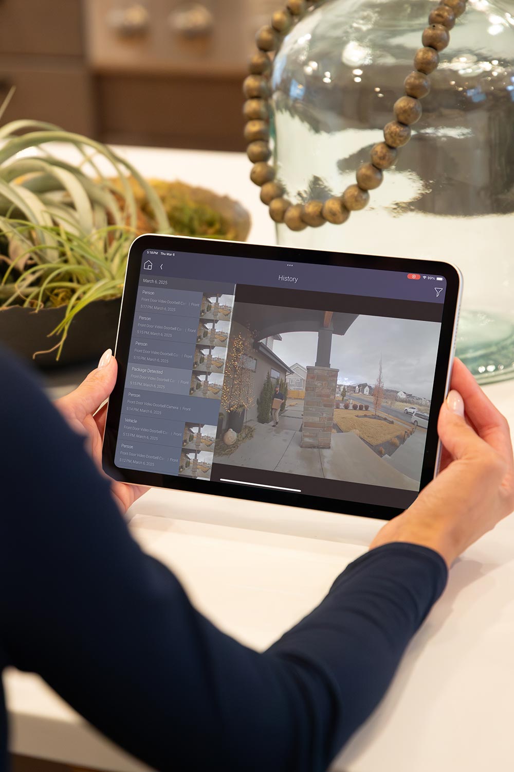 Person holding a tablet displaying front door security camera footage